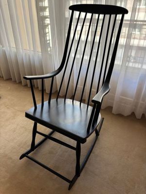 un fauteuil à bascule noir placé devant une fenêtre