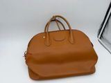 un sac à main en cuir beige posé sur une surface blanche, à côté d'une photo en noir et blanc