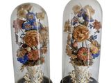 paire de vases décoratifs en verre contenant des fleurs, posés sur des socles en bois