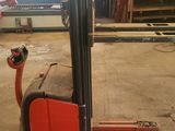 a red forklift sitting in a warehouse with other equipment