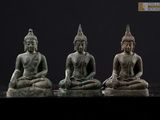 trois statues de bouddhas assis sur une surface noire