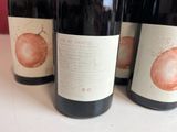 three bottles of wine sitting on a table with a red background