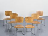 Quatre chaises en bois sont disposées en cercle sur un sol gris.