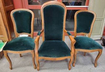 trois chaises recouvertes de velours vert, placées devant une porte