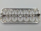 a close up of a silver broochle on a white surface