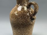 a brown vase with a handle sitting on a table