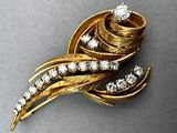an image of a gold brooch with diamonds on a gray surface