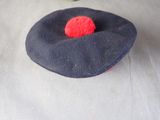 a black hat with a red pom pom on top of it