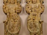une paire de statues en bois sculptées représentant des divinités hindoues, posées sur un plancher en bois