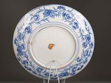 a blue and white plate on a stand on a table