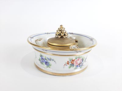 un bol blanc avec un couvercle doré orné de fleurs