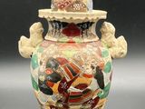a small vase with a bird on top of it