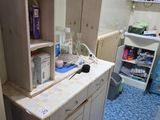 une salle de bains équipée d'un lavabo, d'un miroir, de placards et d'autres éléments posés sur le plan de travail