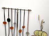 une série de colliers suspendus à un porte-colliers à côté d'un vase