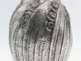 a silver vase with a bird on it on a white surface