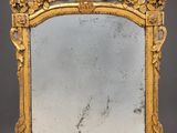 an ornately carved mirror with a gold frame on a grey background