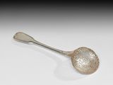 une cuillère en argent ancienne posée sur une surface blanche avec un fond noir