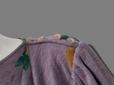 purple sweater with oranges and green leaves on it on a mannequin dummy