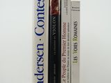 three books are stacked on top of each other on a white surface