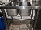 two stainless steel sinks in a kitchen with a blue trash can