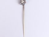 a close up of a diamond and gold pin on a white surface