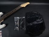 a white electric guitar sitting on a table next to a black bag