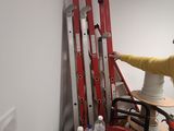 a man that is standing on a ladder in a room