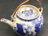 a blue and white teapot with a wooden handle on a table