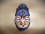 a ceramic mask on a table with a brown background