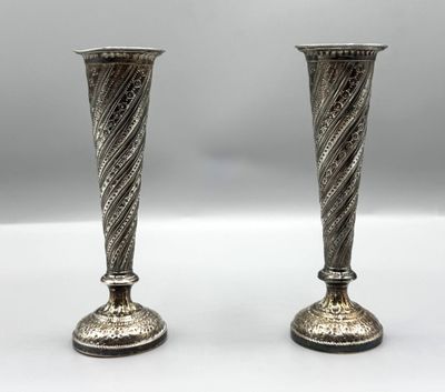 deux vases en argent posés l'un à côté de l'autre sur une table blanche
