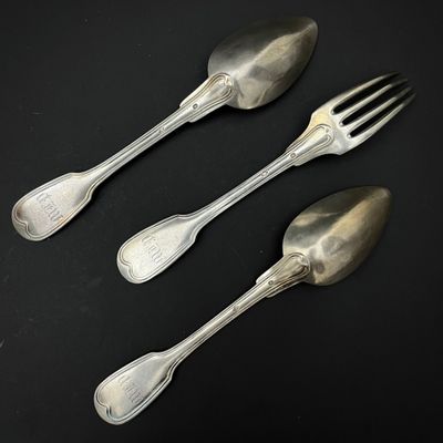 trois cuillères et une fourchette en argent sur une surface noire