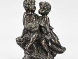 a bronze statue of two children sitting on a rock