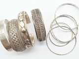 plusieurs bracelets et bagues en argent posés sur une surface blanche