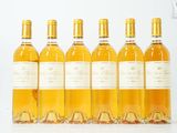 six bouteilles de vin sont alignées sur une surface blanche