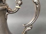a silver coffee pot with a handle on a table