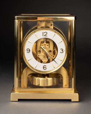a gold clock with a white face on a black background