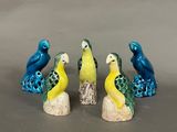three small figurines of birds sitting on top of a wooden stump