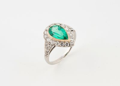 un gros plan d'une bague sertie d'une émeraude en forme de poire entourée de diamants