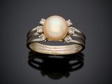 une bague en perles blanches et diamants sur une surface noire