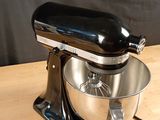 a black mixer on a wooden table with a black background
