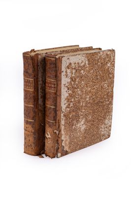 an old book sitting on top of a white surface next to a book