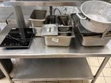 de nombreuses casseroles et poêles posées sur une table dans la cuisine