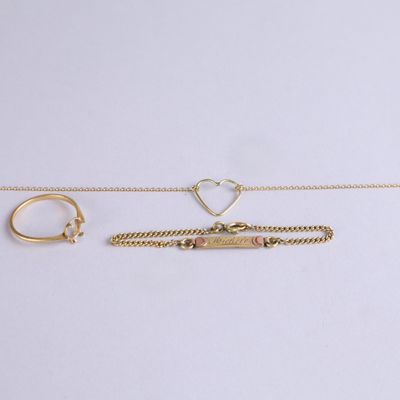 trois bijoux en or posés sur un fond blanc