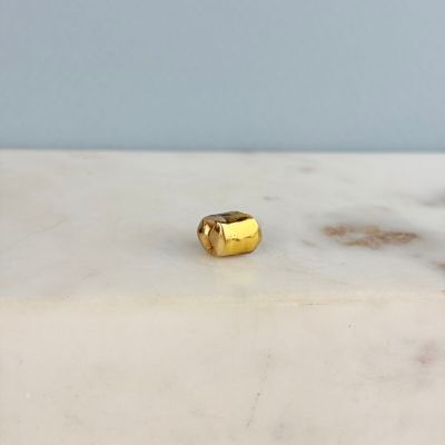 une photo d'une bague plaquée or posée sur une surface en marbre