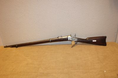 un vieux pistolet avec une crosse en bois posé sur une boîte en carton