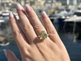 woman ' s hand holding a ring with a green stone on it