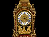 a gold and red clock with roman numerals on it