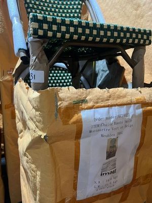 une boîte en carton sur laquelle est posée une chaise et à laquelle est accrochée une pancarte