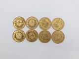 a group of five gold coins sitting on top of a white surface