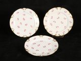 three plates with pink flowers on them on a black background